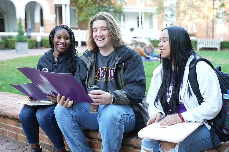 Converse students look at required course materials while sitting outside Wilson Hall.